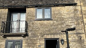 Un edificio de piedra con techo oscuro, un pequeño ventanal de ático, una puerta principal y un buzón.