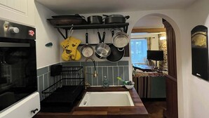 Una cocina con horno, pileta y un colgador para ollas.