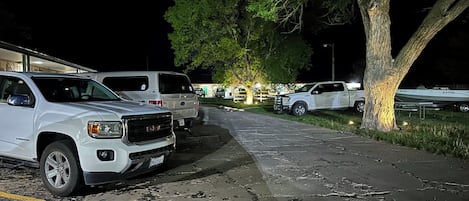 A parking lot with several vehicles, including a white GMC truck, and a large tree.