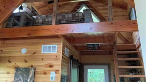 A wooden cabin with a loft bedroom, a ceiling fan, and a door leading outside. - Mohican Cabin Private Getaway (Perrysville)