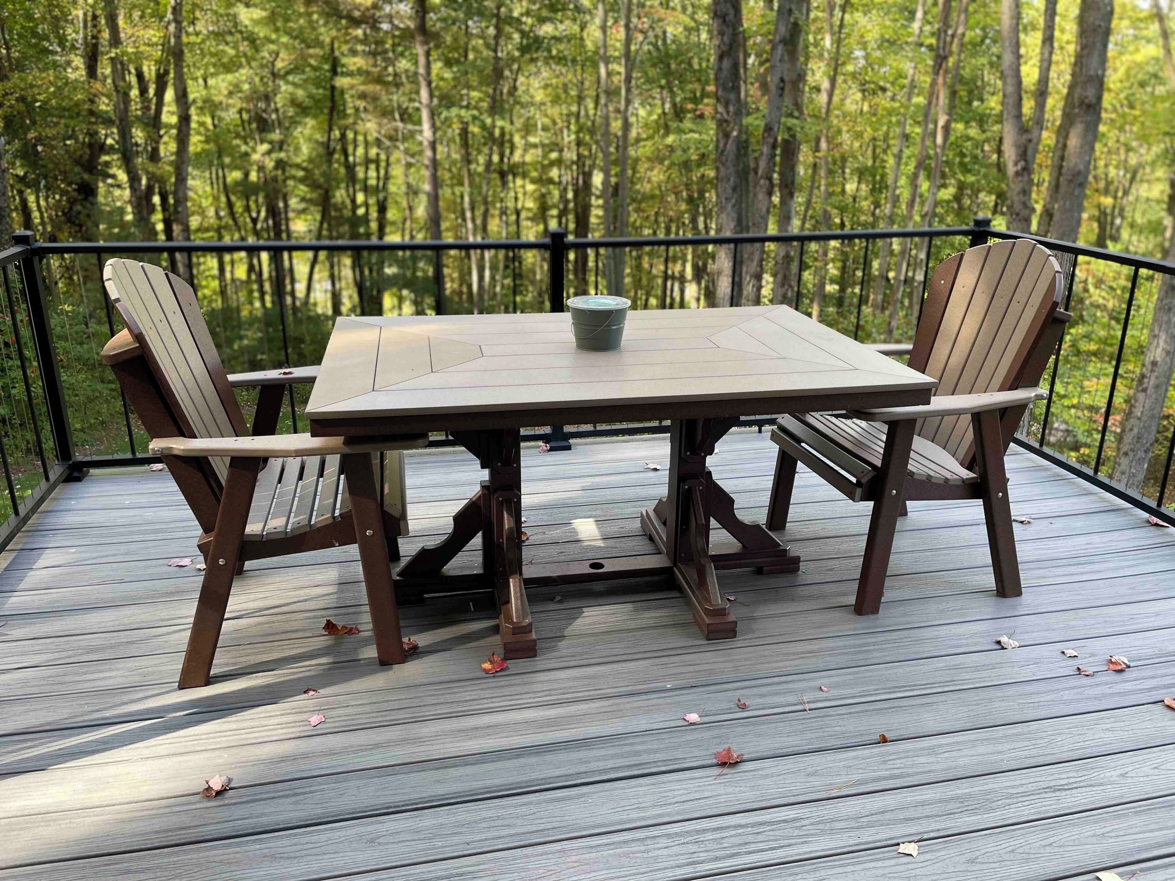 Eine Terrasse mit Tisch und Stühlen, umgeben von einer Brüstung, mit Blick auf einen Wald.