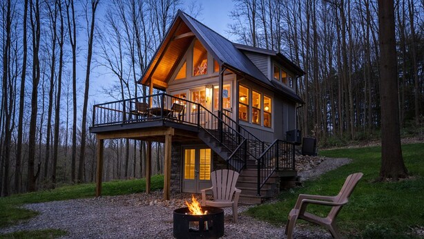 A cabin with a deck, a fire pit, and a chair. - Mohican Cabin Private Getaway (Perrysville)