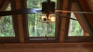 A cabin interior with a dining area, large windows, and a view of the outdoors. - Mohican Cabin Private Getaway (Perrysville)