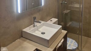 Un bany modern amb un gran mirall, un lavabo i una dutxa envoltat de vidre.
