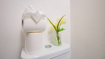 Un inodoro con un rollo de papel higiénico y un pequeño florero con flores.
