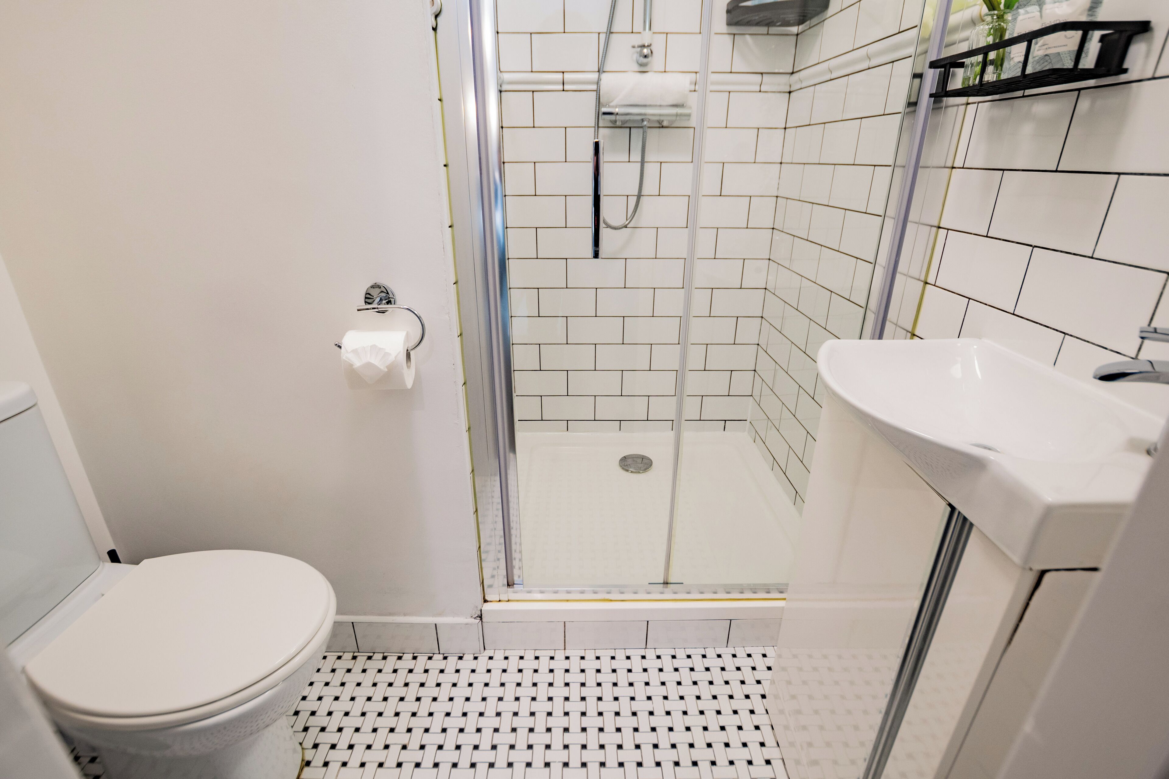 A bathroom with a toilet, a shower with a glass door, and a sink.