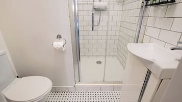 A bathroom with a toilet, a shower with a glass door, and a sink.