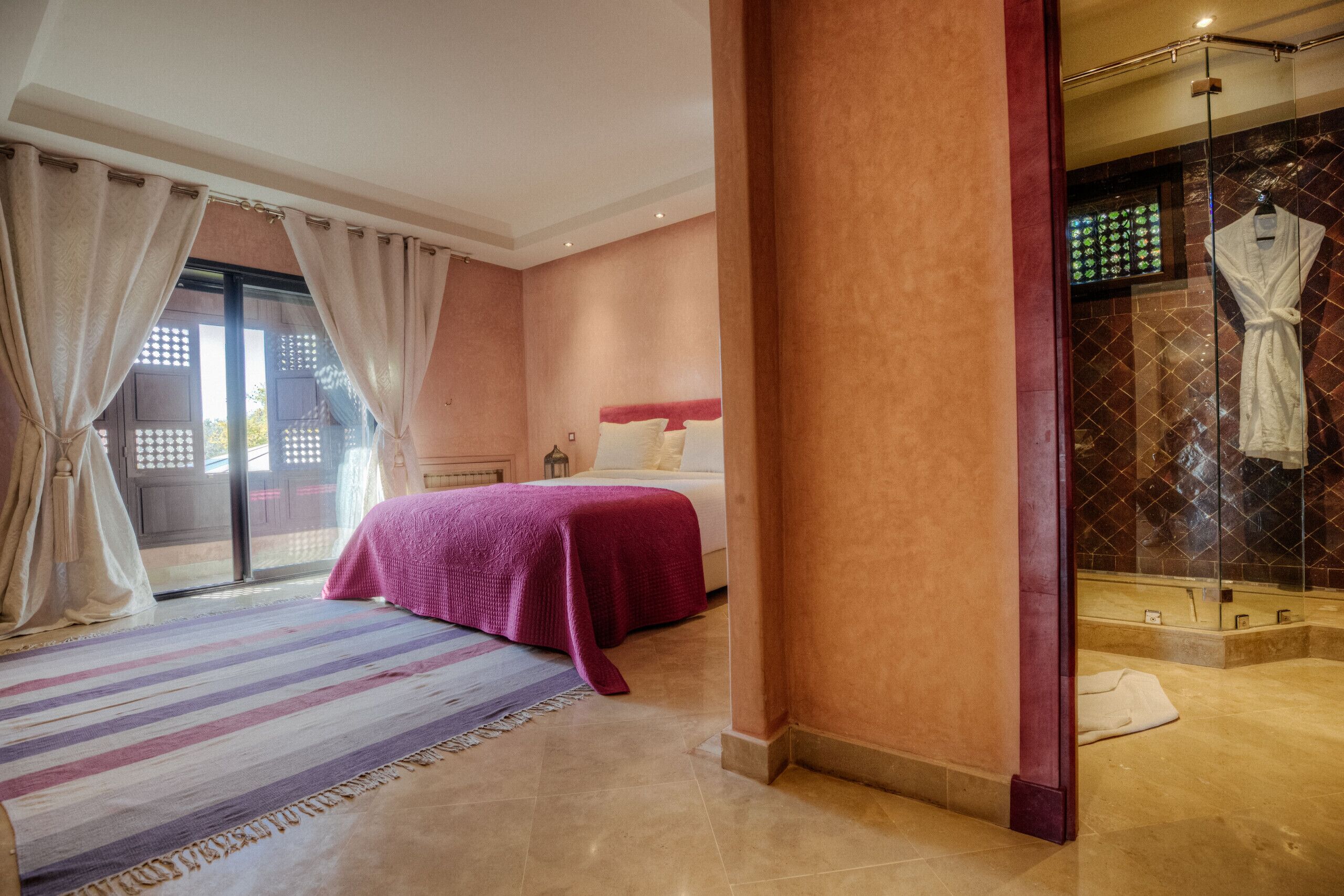 Una habitación de hotel con cama, zona de ducha y vista a través de un ventanal.