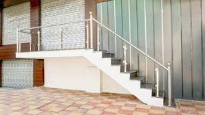 A staircase with a metal railing, a tiled floor, and a wall with vertical lines. - Deluxe Hotel Paradise Peak (Kanpur)