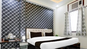A bedroom with a bed, bedside table, lamp, and a window with curtains. - Deluxe Hotel Paradise Peak (Kanpur)