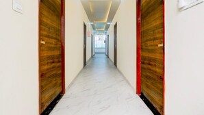 A hallway with wooden doors, a marble floor, and recessed lighting. - Deluxe Hotel Paradise Peak (Kanpur)