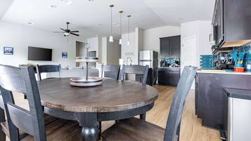 Una cocina moderna con comedor, que incluye una mesa redonda, sillas y un ventilador de techo.
