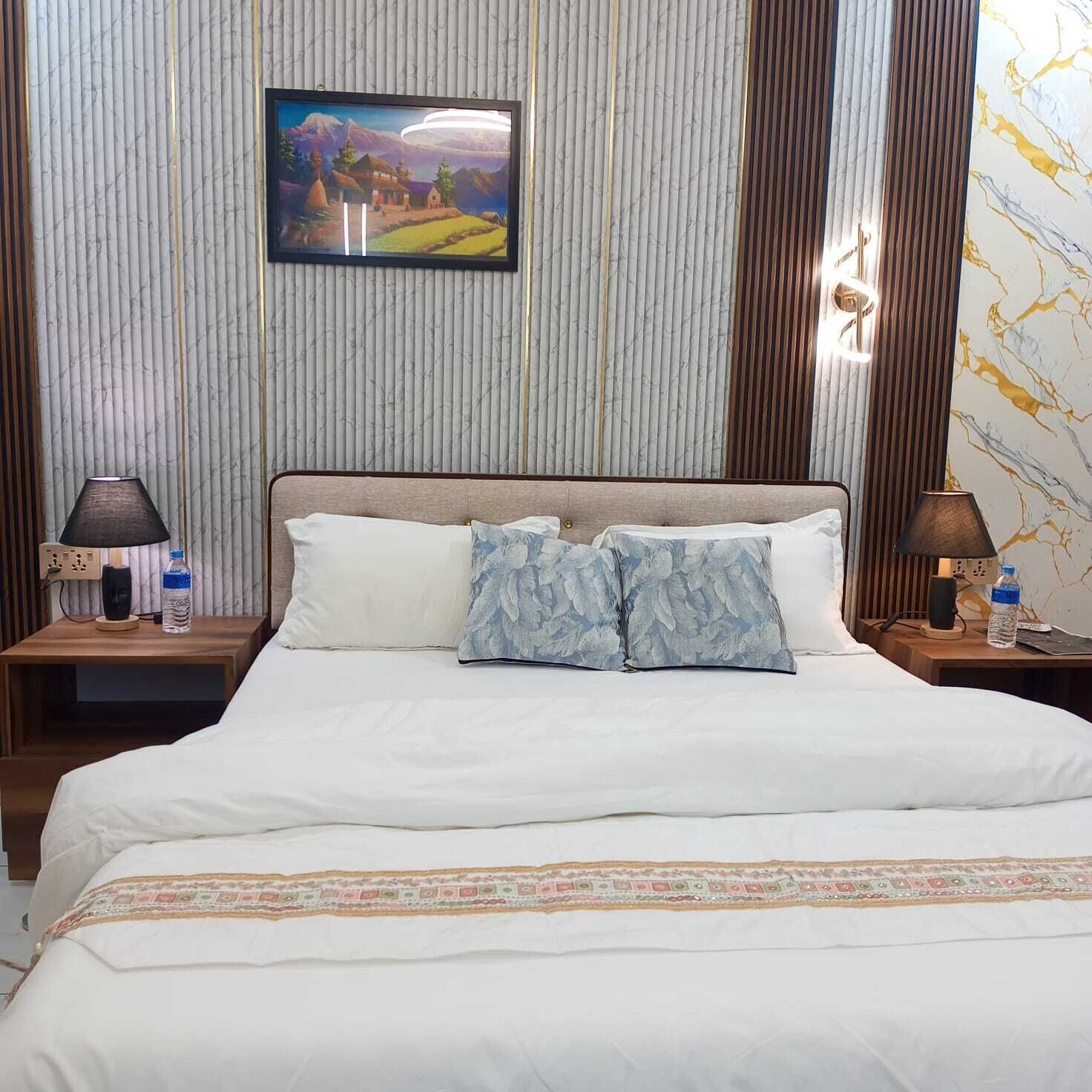 A hotel room with a bed, two nightstands, a painting on the wall, and a marble-patterned wall.