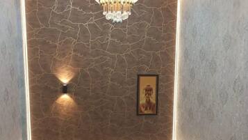 Una habitación con una araña, una lámpara de pared, una estatua de Buda enmarco y dos plantas en macetas.