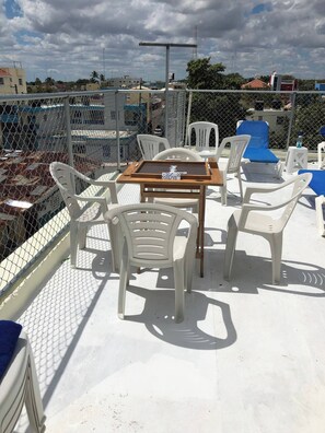 A rooftop terrace with a table and chairs, a metal fence, and a view of buildings and trees. - Higuey Center City, Leslie's Villa (Higuey)