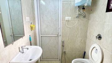 A bathroom with a sink, toilet, shower, and a water heater.
