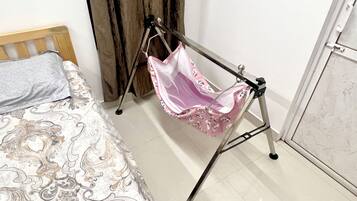 A bed with patterned bedding, a wooden headboard, a pink bag on a stand, a curtain, and a tiled floor.