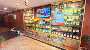Een winkel met schappen vol kruideninfusies en thee, een televisiescherm en een bord waarop Darjeeling Groene Thee staat aangegeven.