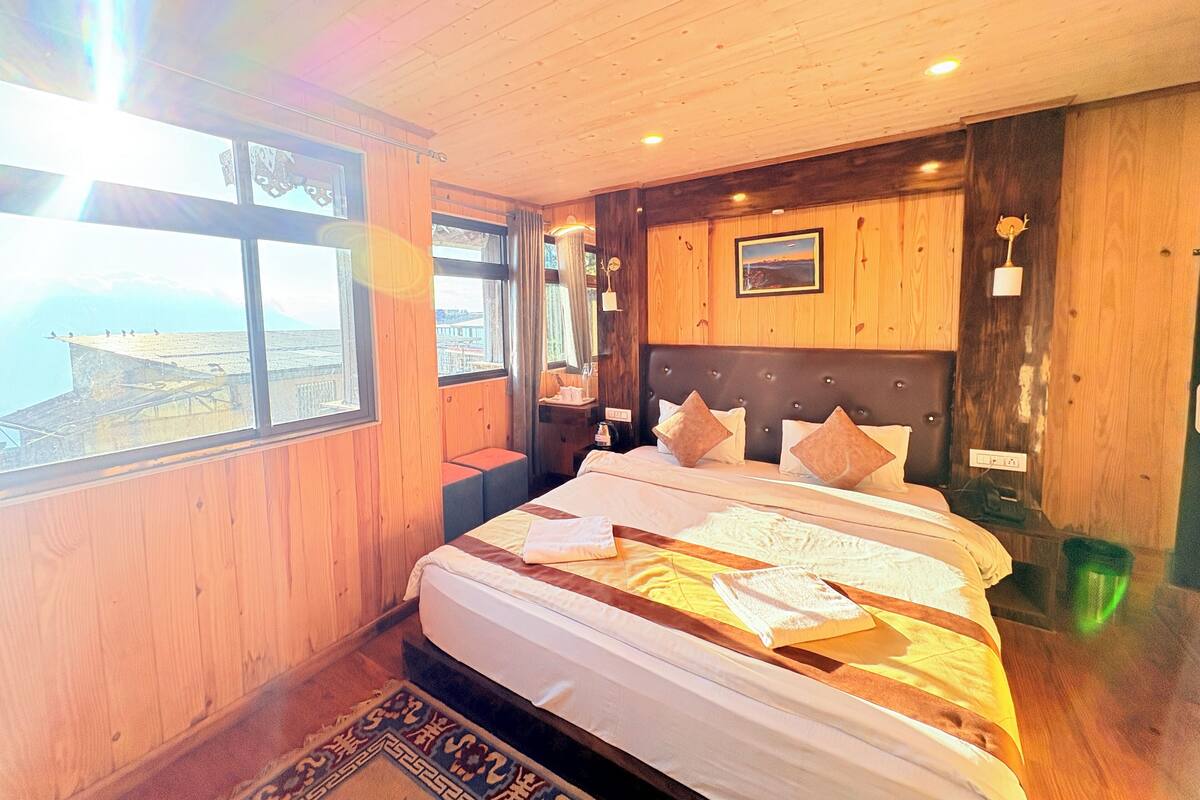 Un dormitorio con una cama grande, paredes de madera, vistas por la ventana y techo de madera.