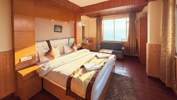 Een hotelkamer met een groot bed, een bank, een bureau en een raam met uitzicht.