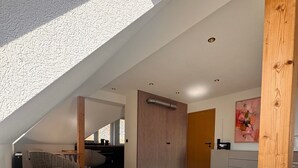 A modern loft bedroom with a sloped ceiling, a sofa bed, a wooden floor, and a large window. - Apartment 'Design Dachgeschoss' with Shared Garden and Wi-Fi (Eilenburg)