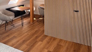 A modern loft bedroom with a sloped ceiling, a skylight, a wooden panel wall, a built-in heater, and a dining area with a table and chairs. - Apartment 'Design Dachgeschoss' with Shared Garden and Wi-Fi (Eilenburg)