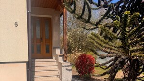 A house with a stone staircase leading to a wooden door, surrounded by various plants and a large tree. - Apartment 'Design Dachgeschoss' with Shared Garden and Wi-Fi (Eilenburg)