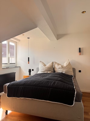Un dormitorio con cama, ventana y lámpara en el techo.