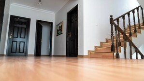 A spacious room with hardwood flooring, a staircase with wooden balusters, and two black doors. - 6 Rooms Stone Villa With Private Pool - Sea and Mountain Views (Kemer)