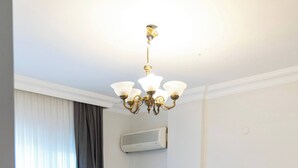 A bedroom with a bed, a nightstand, a lamp, a chandelier, and an air conditioning unit. - 6 Rooms Stone Villa With Private Pool - Sea and Mountain Views (Kemer)