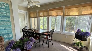 Ein Wintergarten mit Tisch und Stühlen, großen Fenstern, einem Deckenventilator und einer Wand mit einer Liste von Gegenständen.