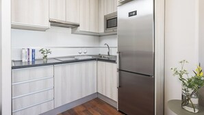 Una cucina moderna con mobili chiari in legno, un frigorifero in acciaio inossidabile, un forno a microonde e un lavello.