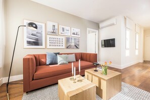 Ein Wohnzimmer mit einer Couch, einem Couchtisch, einer Stehlampe und gerahmten Bildern an der Wand.