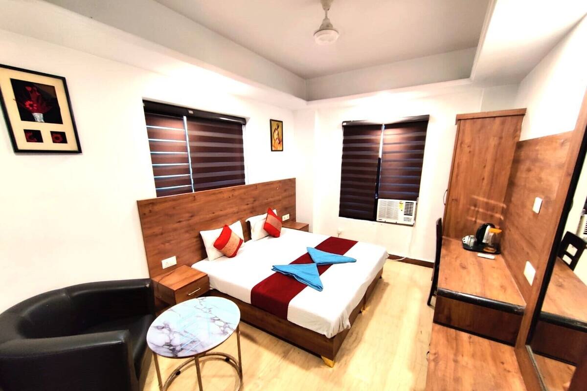 A bedroom with a bed, bedside tables, a small round table, a chair, and a wardrobe.