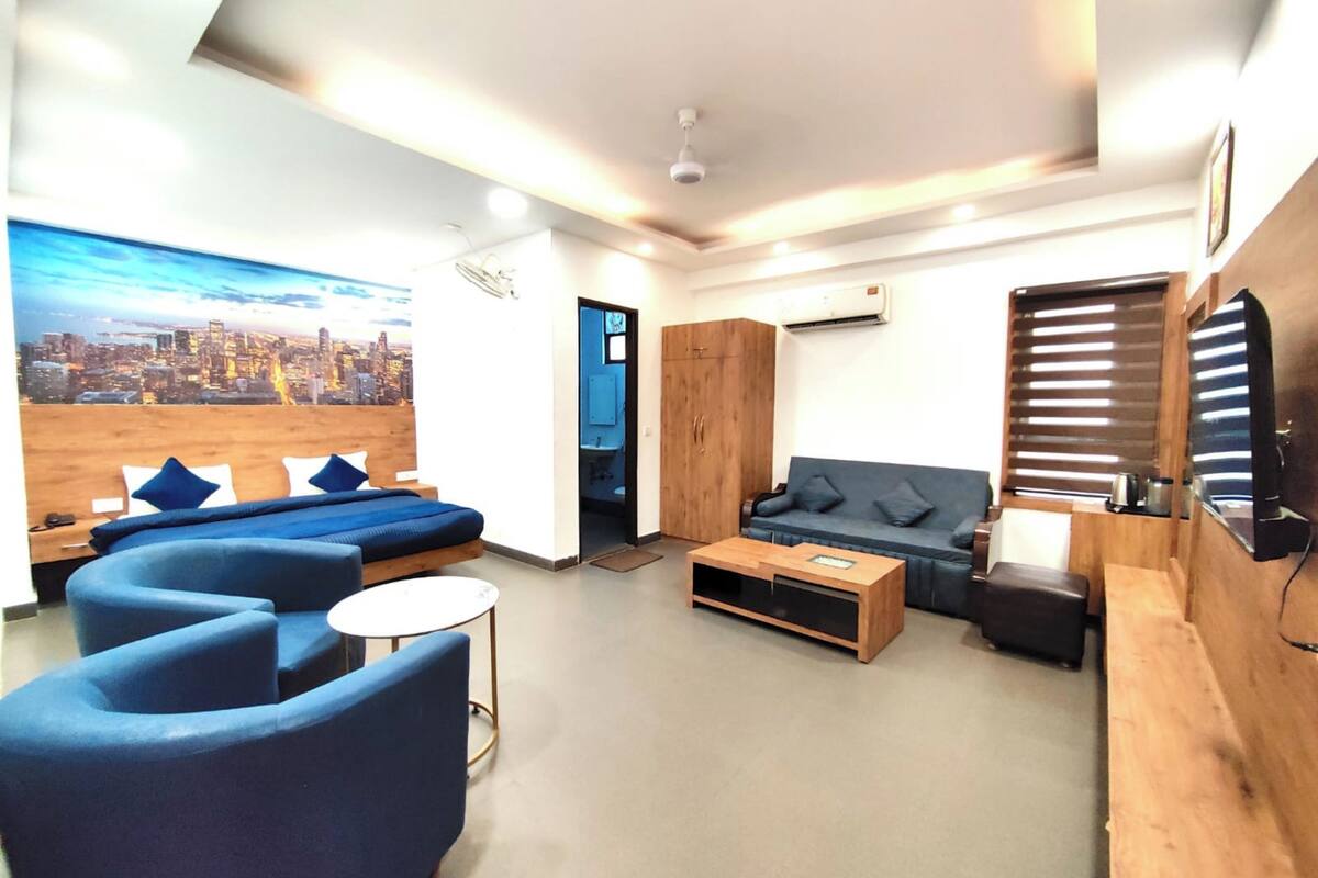 A modern hotel room with a cityscape mural, a sofa, a coffee table, and a TV.