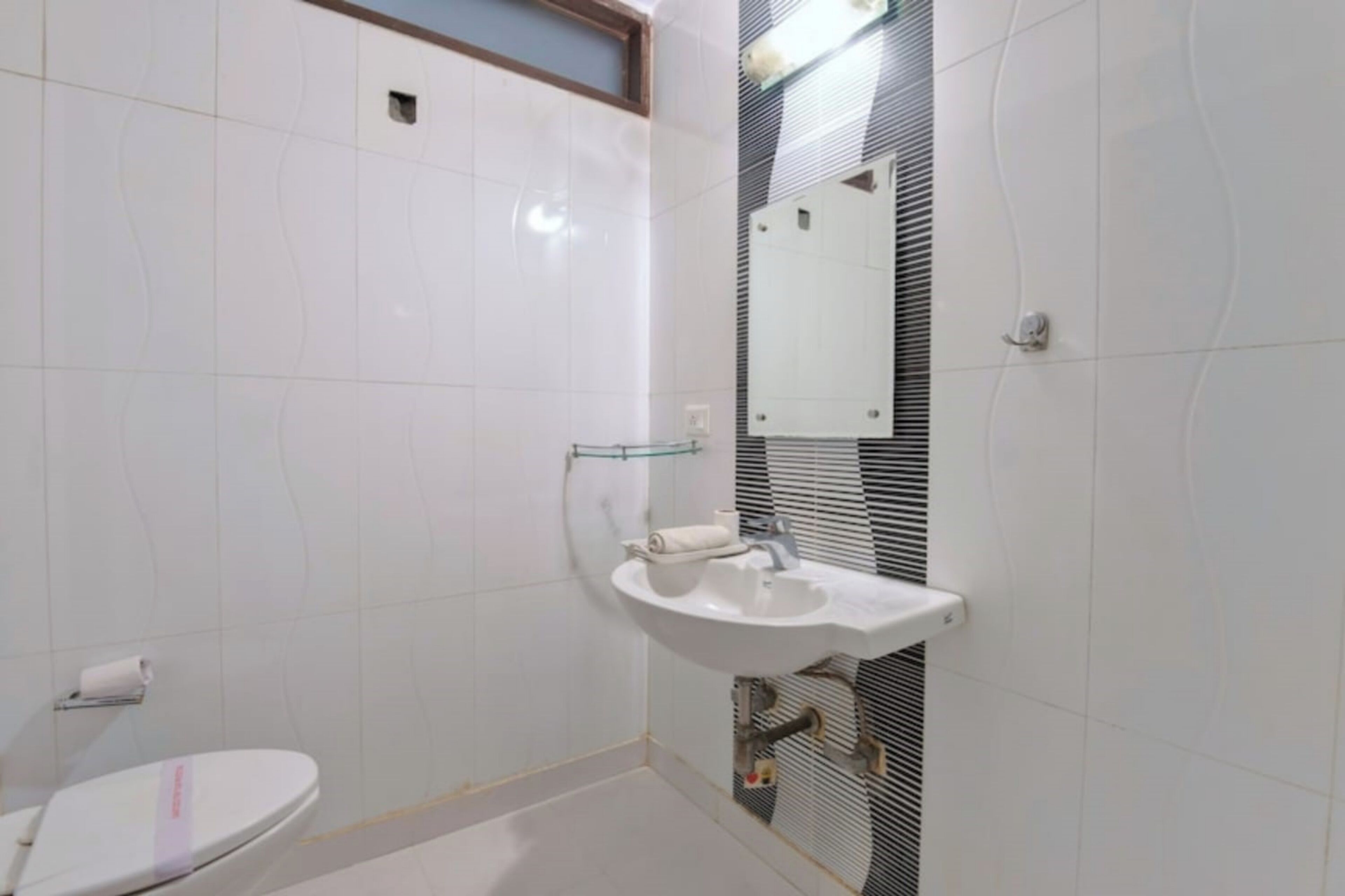 Un baño con inodoro, lavamanos y espejo.