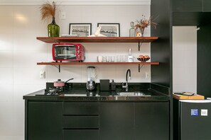 A modern kitchen with black cabinets, a red microwave, and a coffee maker. - Modern | Fast Wi-Fi | On the Gastronomic Route (Florianópolis)