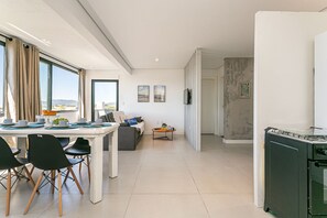 A modern kitchen with a dining area, large windows, and a view of the outdoors. - Beautiful view | in the heart of Campeche (Florianópolis)