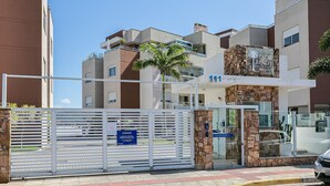 Ein modernes Gebäude mit Stein-Fassade, einer Palme und einem Schild mit der Aufschrift 'Palm Beach Residence'.