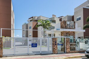 Un bâtiment moderne avec une façade en pierre, un palmier et une enseigne indiquant « Palm Beach Residence ».