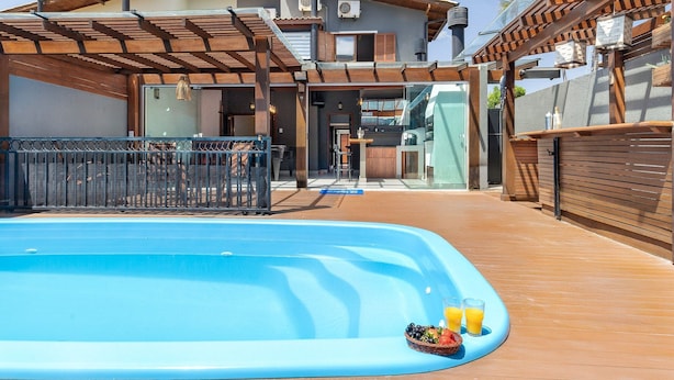 Ein Pool mit Holzterrasse, überdachter Außenbereich und Gebäude im modernen Stil.
