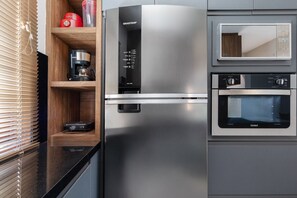 A stainless steel refrigerator with a digital display, a microwave, and a coffee maker on a wooden shelf. - Beachfront house: pool, BBQ, jacuzzi & more (Florianópolis)