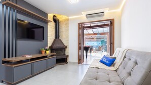 Ein modernes Wohnzimmer mit Fernseher, integriertem Unterhaltungssystem, Kamin und einer Couch mit Kissen.