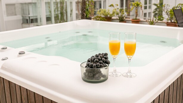 A hot tub with two glasses of orange juice and a bowl of grapes. - Penthouse with jacuzzi near the sea Campeche (Florianópolis)