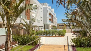 A modern building with balconies, surrounded by palm trees and a landscaped garden. - Penthouse with jacuzzi near the sea Campeche (Florianópolis)