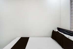 A single bed with a white and dark brown bedspread, a wooden headboard, and a window with blinds. - Deluxe R J Residency (Hyderabad)