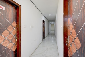 A corridor with wooden doors, white walls, and a tiled floor. - Deluxe R J Residency (Hyderabad)