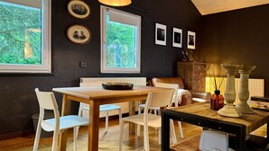A dining area with a wooden table and chairs, a radiator, and framed pictures on the wall. - Cozy Durbuy Chalet With Fireplace (Rendeux)