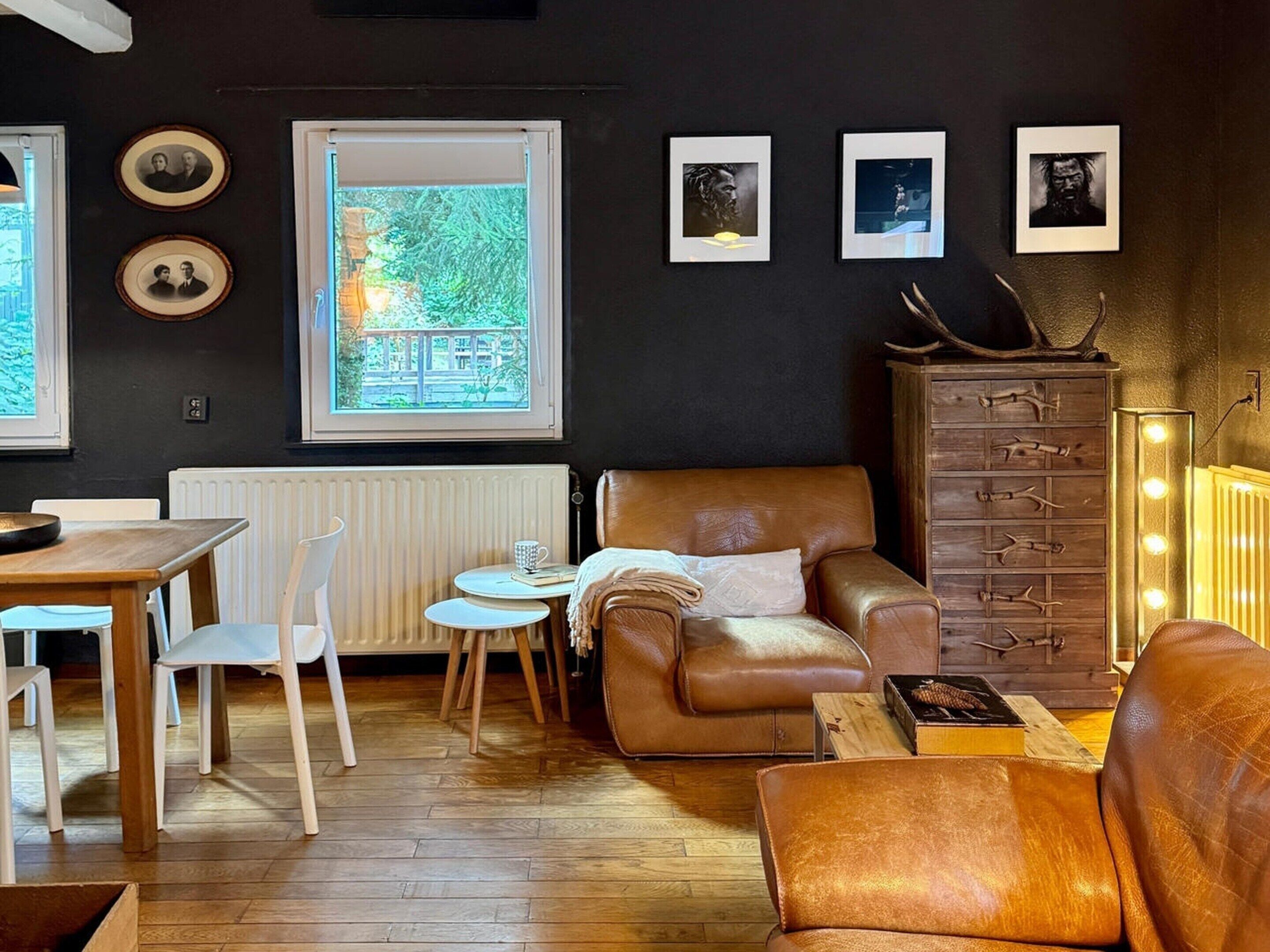 A cozy living room with a brown leather sofa, a wooden cabinet with lights, and framed pictures on the wall.