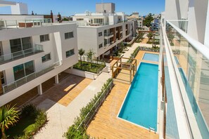 Un bâtiment moderne doté de nombreux balcons, d’une piscine sur le toit et offrant une vue dégagée sur les environs.